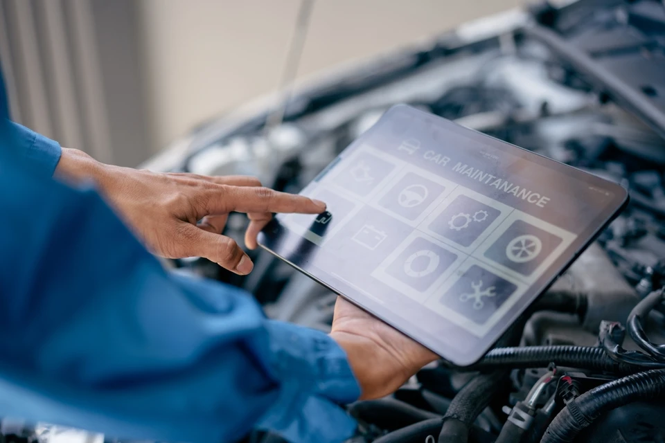 Réparateur mécanique automobile utilisant une tablette pour vérifier la salle des machines, vérifier le kilométrage de la voiture, le changement d'huile, le service auto de voiture, le concept de service d'entretien automobile