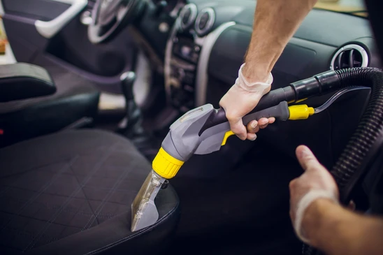 Int&eacute;rieur de v&eacute;hicule automobile, personne utilisant un aspirateur professionnel pour nettoyer la sellerie
