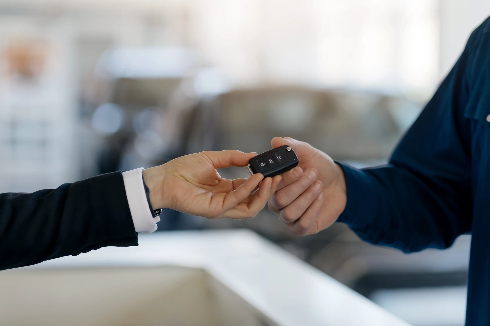 Gros Plan De Vendeur De Voiture Donnant Des Clés À Un Client Mâle Dans Un Showroom