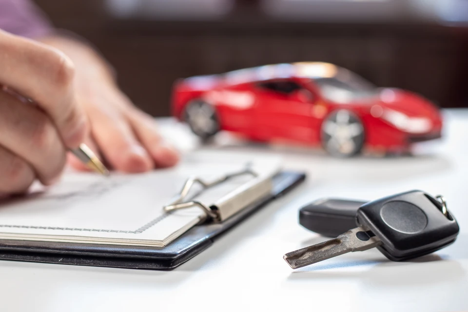 Couple souriant assis face à un conseiller dans un showroom automobile, examinant des documents contractuels sur une table en bois